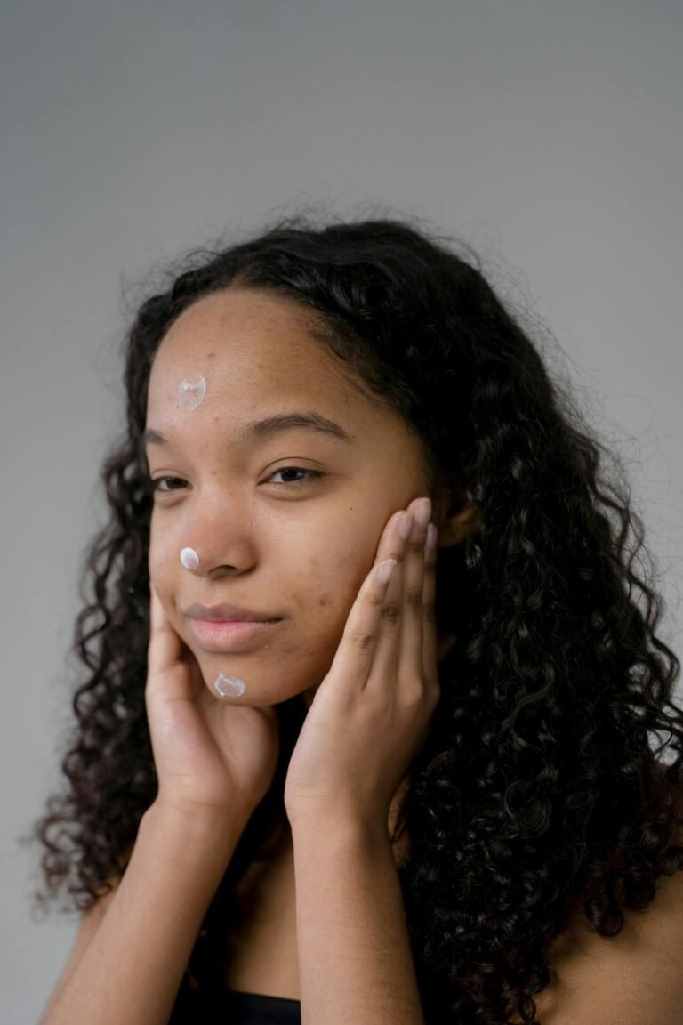 Portrait of a woman applying skincare, highlighting beauty and hydration with a serene expression.